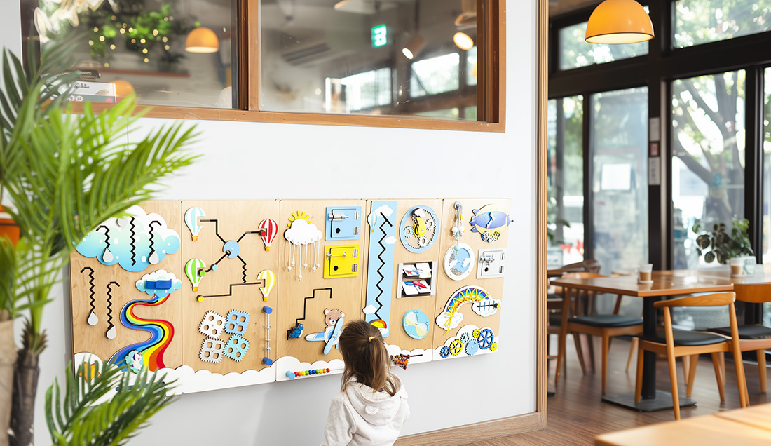 Wall mounted busy board fixed to a wall for toddler use Wall mounted busy board securely fixed to a wall, used by a toddler without taking up floor space